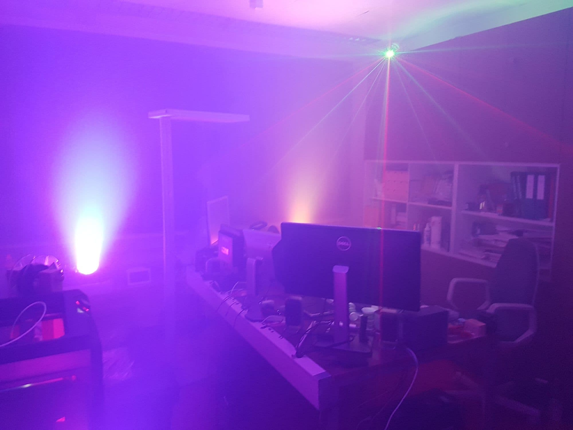 The Batcave — room glowing purple with party lights, lasers, and monitors