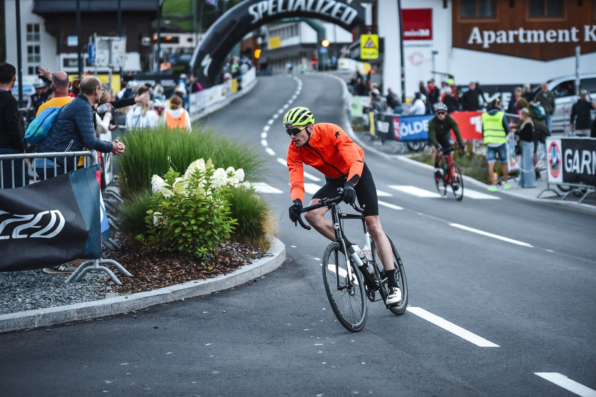 Julian approaching the finish line in Solden, orange jacket, Specialized banner
